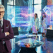 Maik Marx in violettem Anzug in einem futuristischen Kristallbüro mit zwei Frauen in holografischen Outfits.