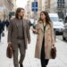 Lia und Maik gehen mit Laptoptasche eine Stadtstraße entlang, unterwegs zum Termin