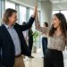 Lia und Maik klatschen sich im Büro freudig ab (High-Five)