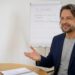 KI-generiert: Coach erklärt in einem hellen Büro, wie man eine Lücke im Lebenslauf darstellt